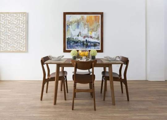 A brown wooden dining table with four chairs and a painting on the wall.