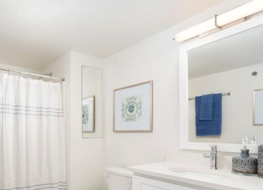 A white bathroom with a toilet, sink, and shower curtain.