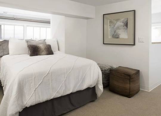 A bedroom with a large bed and a framed picture on the wall.