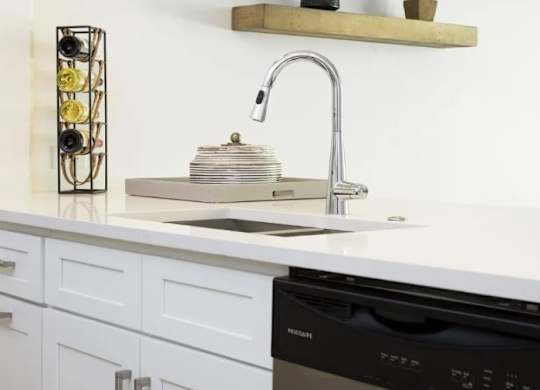 A kitchen with a black dishwasher and a sink with a silver faucet.