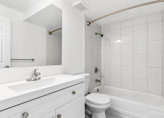 A white bathroom with a toilet, sink, and bathtub.
