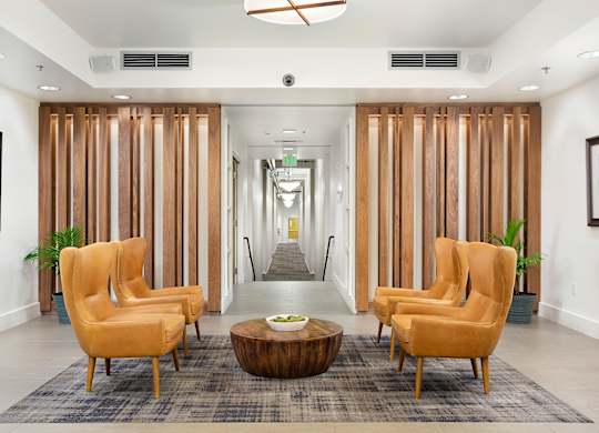 A hallway with a row of chairs and a coffee table.