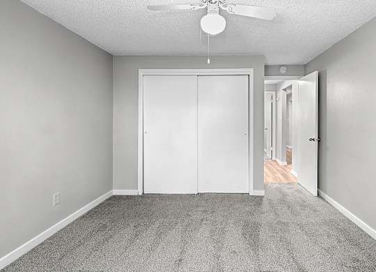 A room with a ceiling fan and a white door.