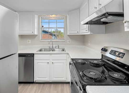 A kitchen with white cabinets and a black stove top.