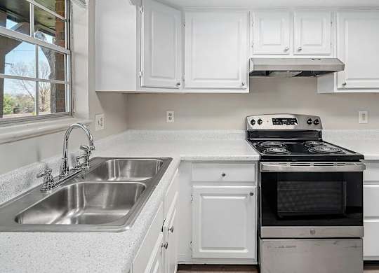 A white kitchen with a stove and sink.