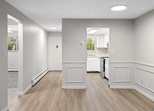 A kitchen area with white cabinets and a wooden floor.