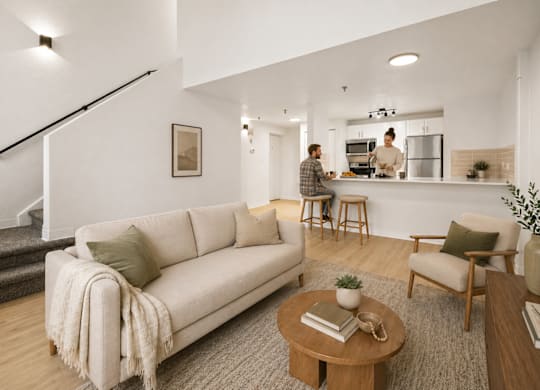 A living room with a couch, a coffee table, and a person in the kitchen.