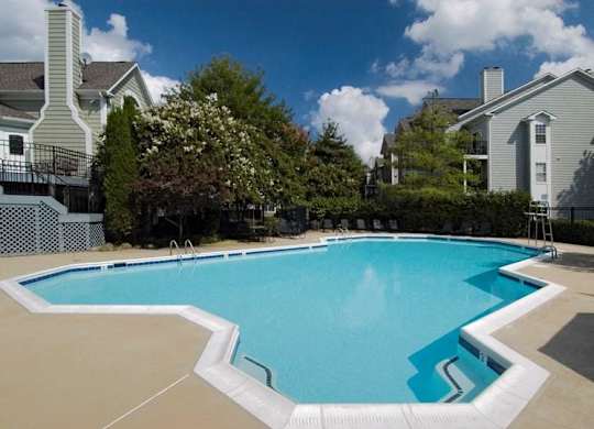 A large swimming pool surrounded by a white fence and trees.