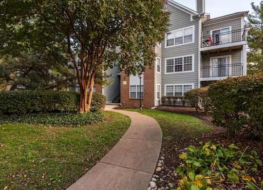 A walkway leads to a building with a balcony.