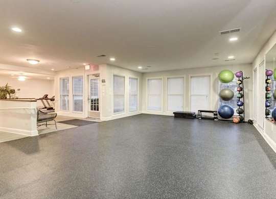 A spacious room with a grey floor and white walls, equipped with exercise balls and a bench.