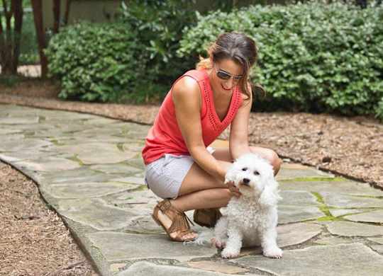 a woman is petting a white dog on the ground