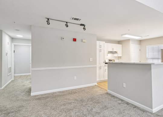 A spacious living room with a kitchen area in the background.