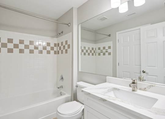 A white bathroom with a checkered tile wall.