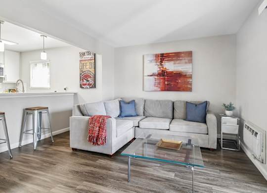 A living room with a white couch and a red and white painting on the wall.
