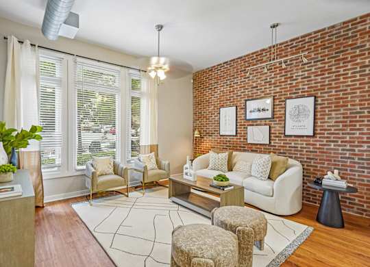 A living room with a white couch, a chair, a table, and a plant.
