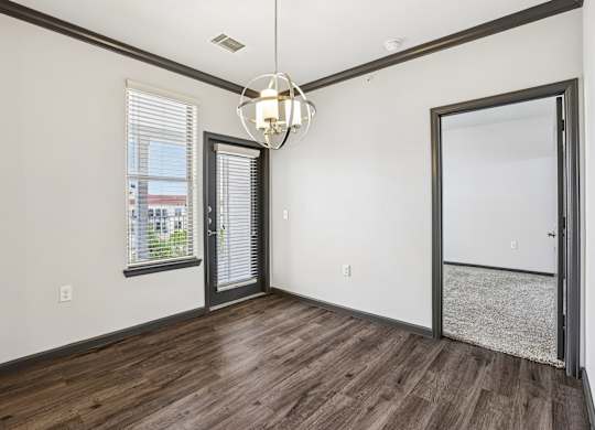 A room with a wooden floor and a chandelier hanging from the ceiling.