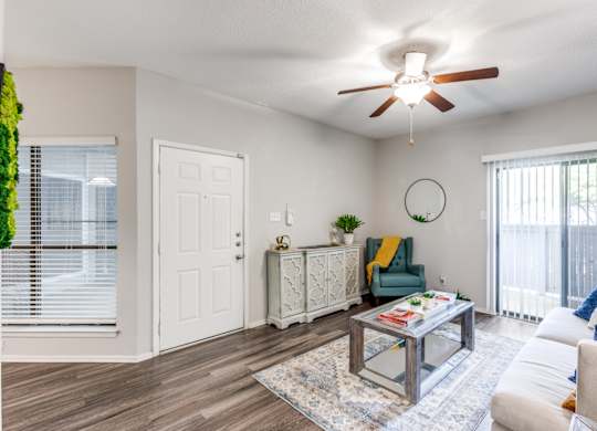 A living room with a white ceiling fan and a glass coffee table.