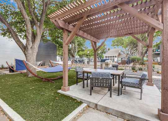 A wooden pergola with a hammock under it.