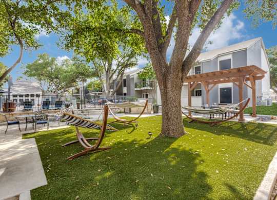 A park with a bench and a tree in front of a building.