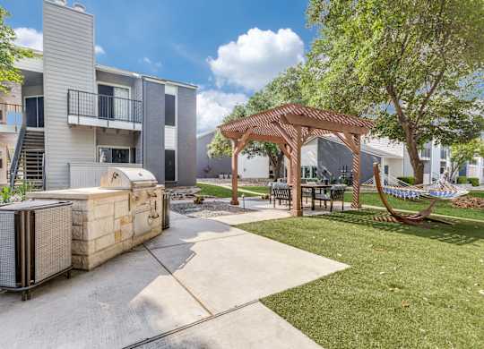 A patio area with a grill and seating area in front of apartment buildings.