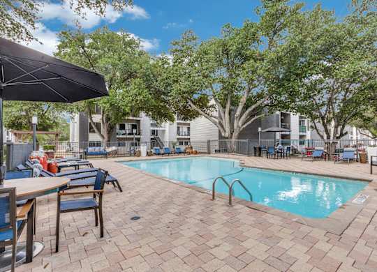 A pool surrounded by chairs and umbrellas.