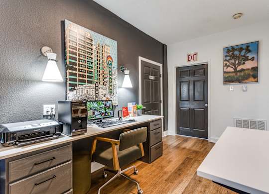 a desk with a computer and a printer in a room with a door that is open