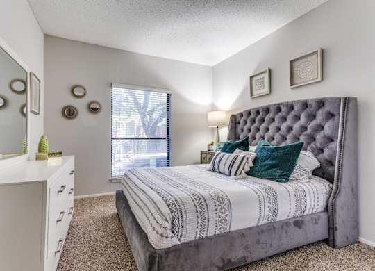 a bedroom with a large bed and a dresser with a mirror