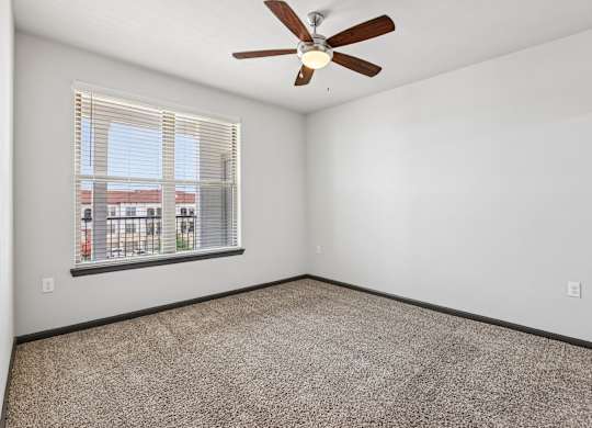 A room with a ceiling fan and a window with blinds.