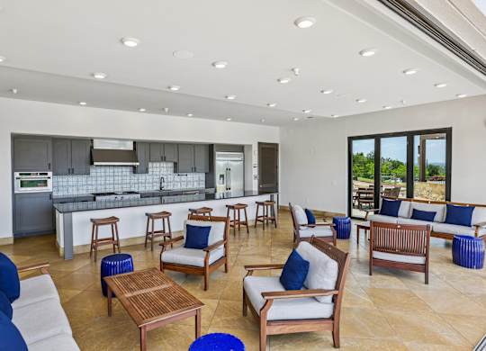 A spacious living room with a kitchen in the background.