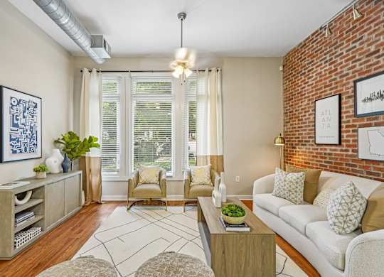 A living room with a white couch, a wooden coffee table, and a brick wall.