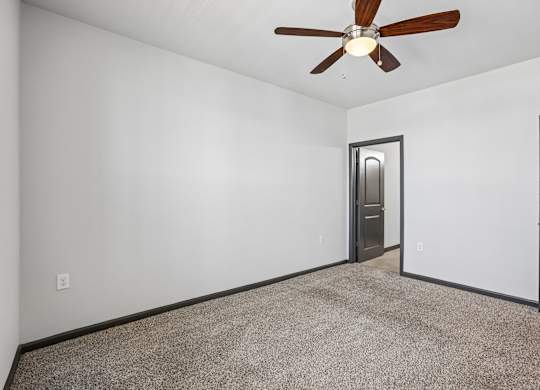 A room with a ceiling fan and carpeted floor.