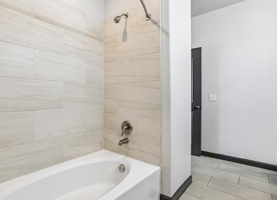 A white bathtub in a bathroom with a shower head above it.