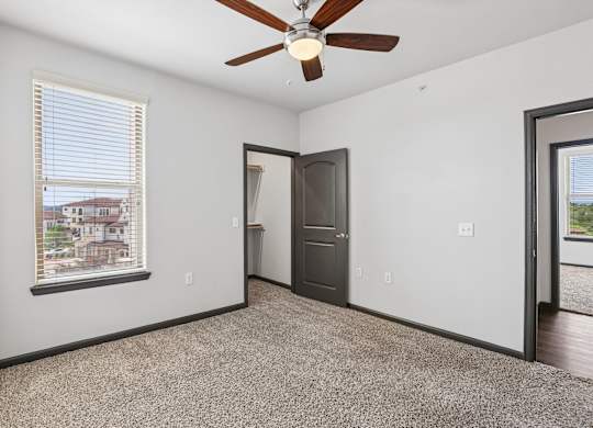 A room with a ceiling fan and a window with blinds.