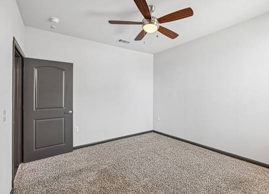 A room with a ceiling fan and a door.