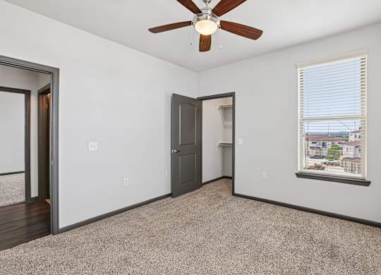 A room with a ceiling fan and a window with blinds.