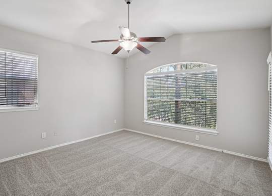 A room with a ceiling fan and a window with blinds.