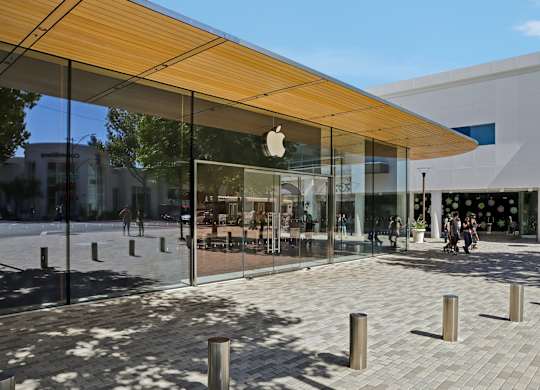 The Apple store has a glass facade and a wooden awning.