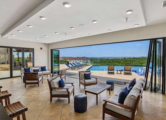 A modern living room with a view of the pool and outdoor furniture.