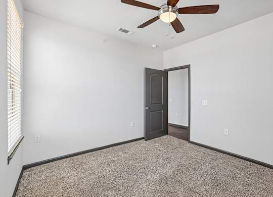 A room with a ceiling fan and carpeted floor.