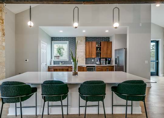 a kitchen with a large white island and green chairs at Canyon Ridge, Austin