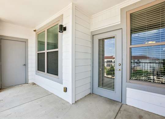 A white house with a grey door and a window with blinds.