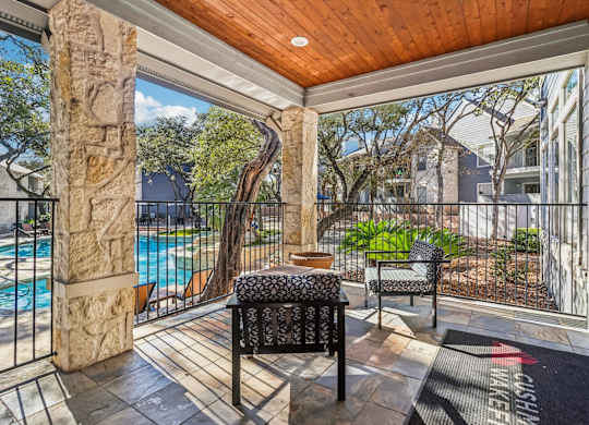 A patio with a black chair and a stone pillar.
