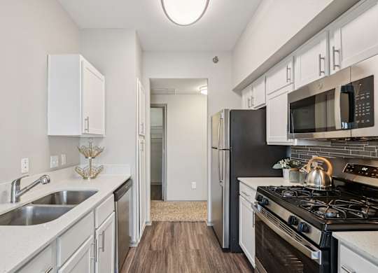 A kitchen with a black refrigerator and stove top oven.