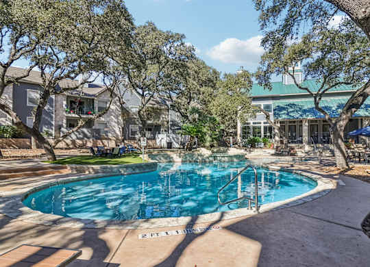 A swimming pool surrounded by trees and a building in the background.