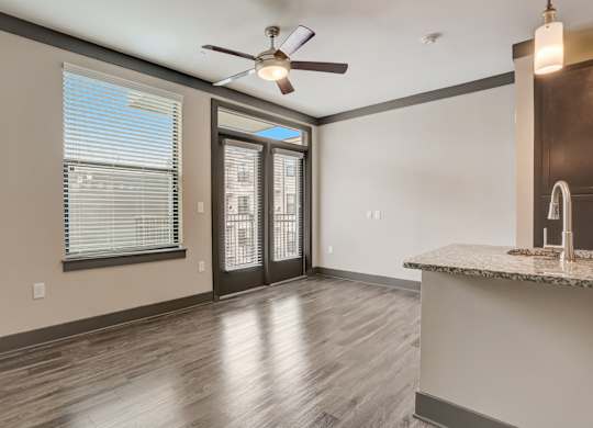 Pet-Friendly Apartments in Nashville, TN- Octave Apartments- Living Room with patio doors large windows wood style flooring and a ceiling fan