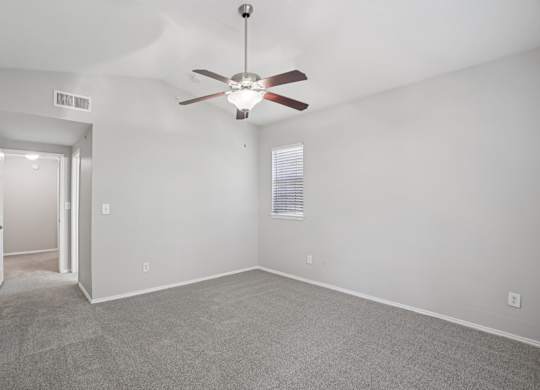 A room with a ceiling fan and carpeted floor.