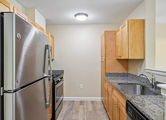 A kitchen with a stainless steel refrigerator and wooden cabinets.