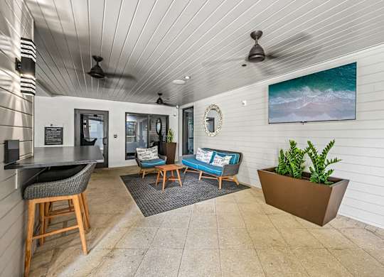 A living room with a ceiling fan and a painting of a beach scene on the wall.