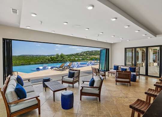 A modern living room with a view of a pool and trees.