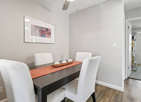 A modern dining room with a black table and white chairs.